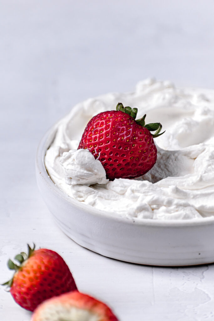 mascarpone frosting in white bowl with strawberry