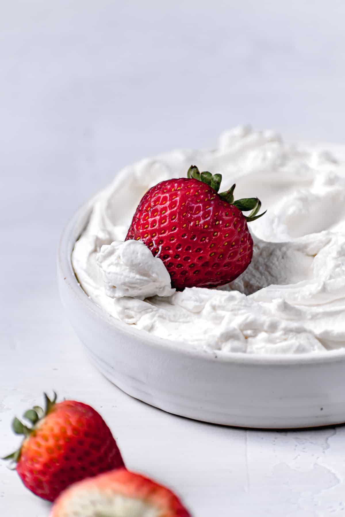 mascarpone frosting in white bowl with strawberry.