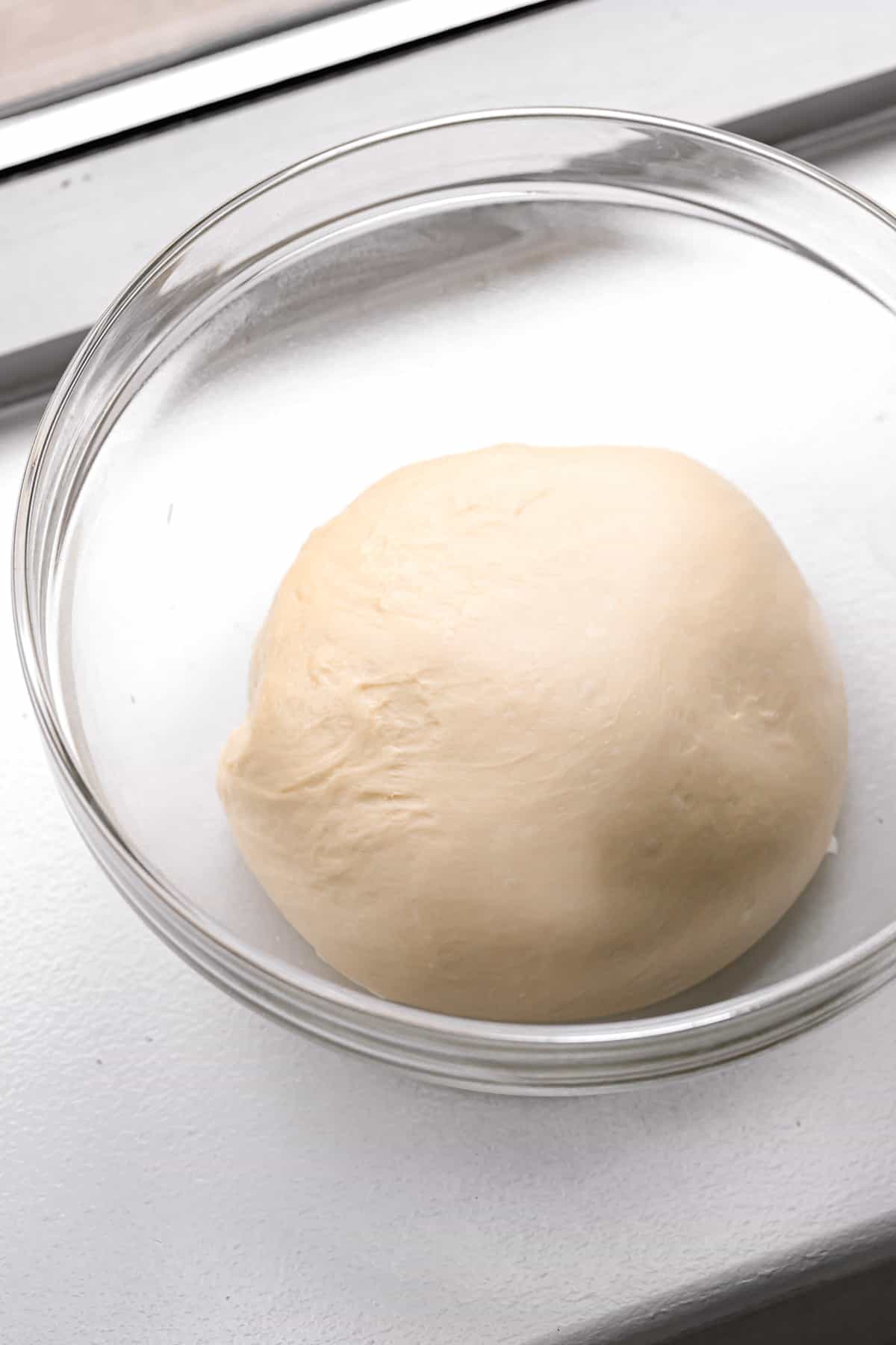 brioche dough in glass bowl .