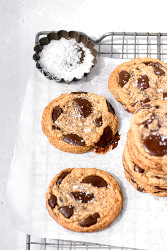 cookies on parchment lined wire rack with bowl of flaky sea salt