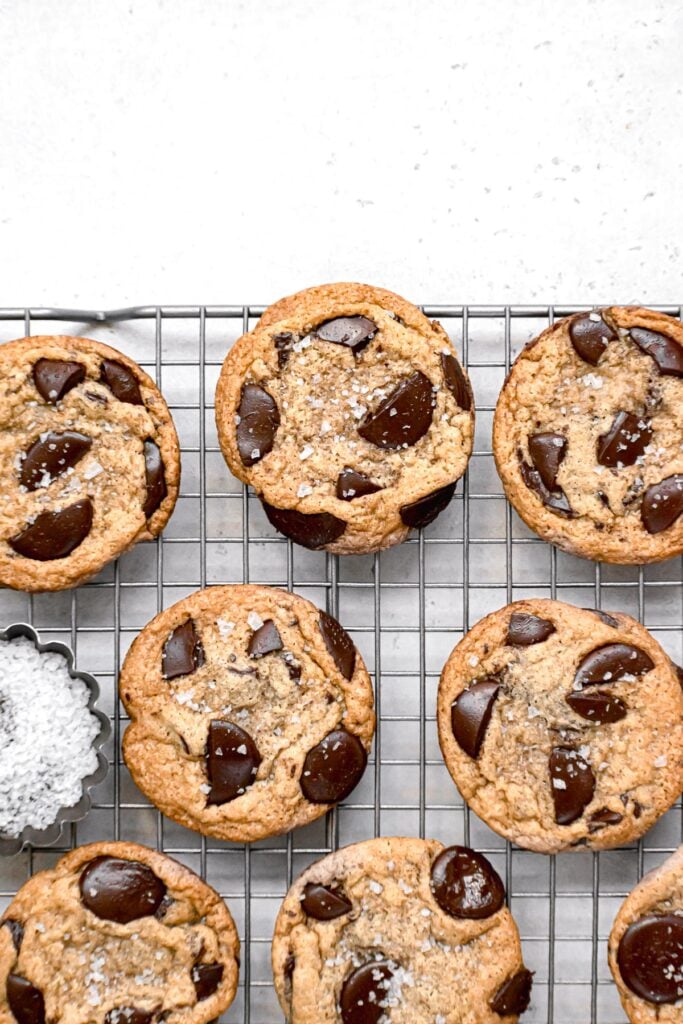 chocolate chip cookies on wire rack with bowl of flaky sea salt