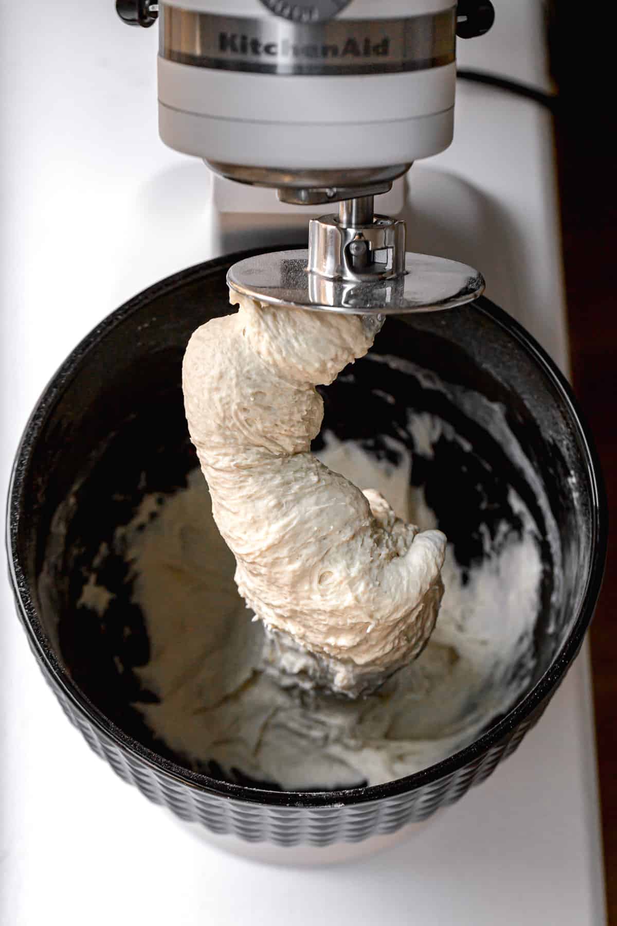 bagel dough wrapped around dough hook in stand mixer.