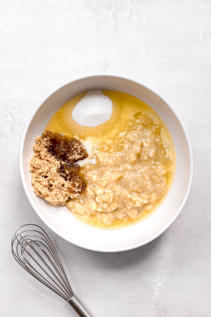 mashed banana, melted butter, and sugars in white bowl