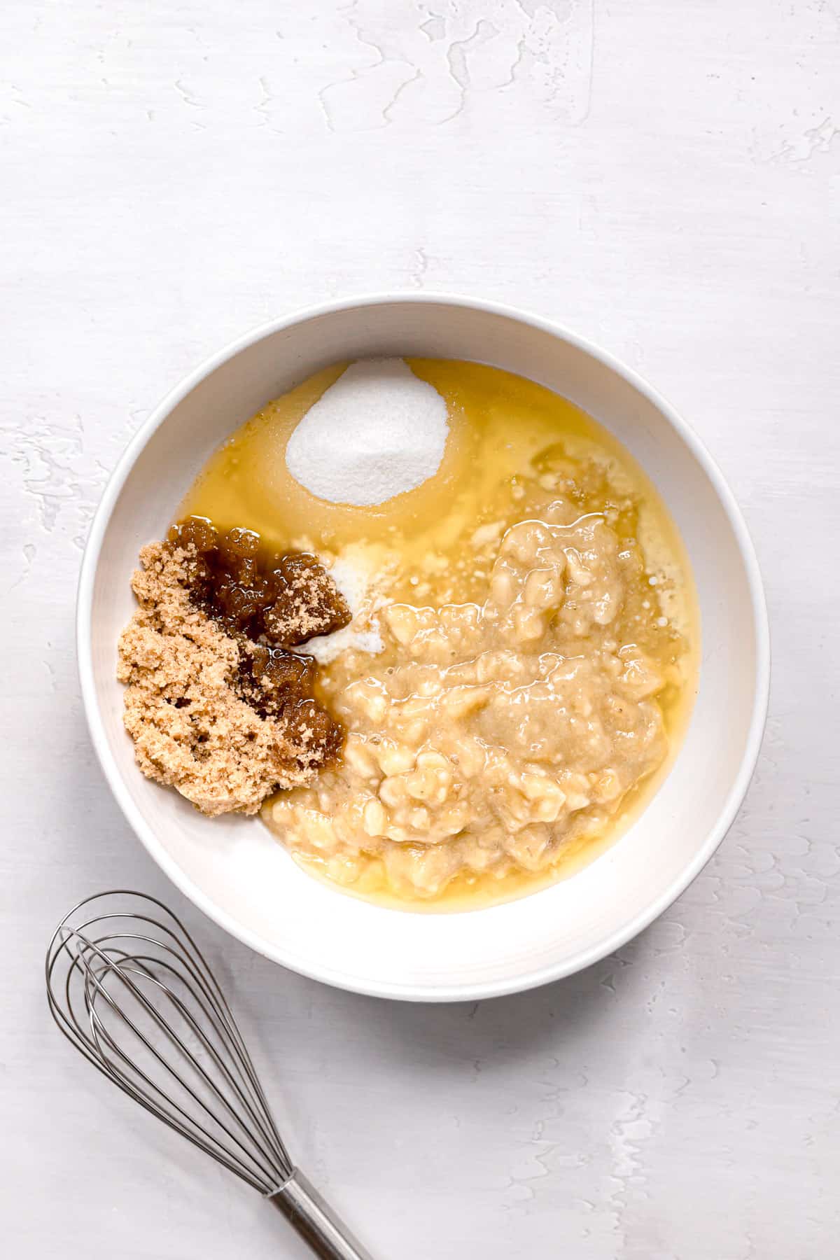 mashed banana, melted butter, and sugars in white bowl.