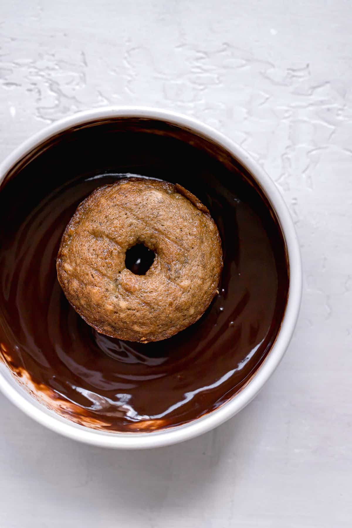 mini banana bread donut in bowl of chocolate glaze.