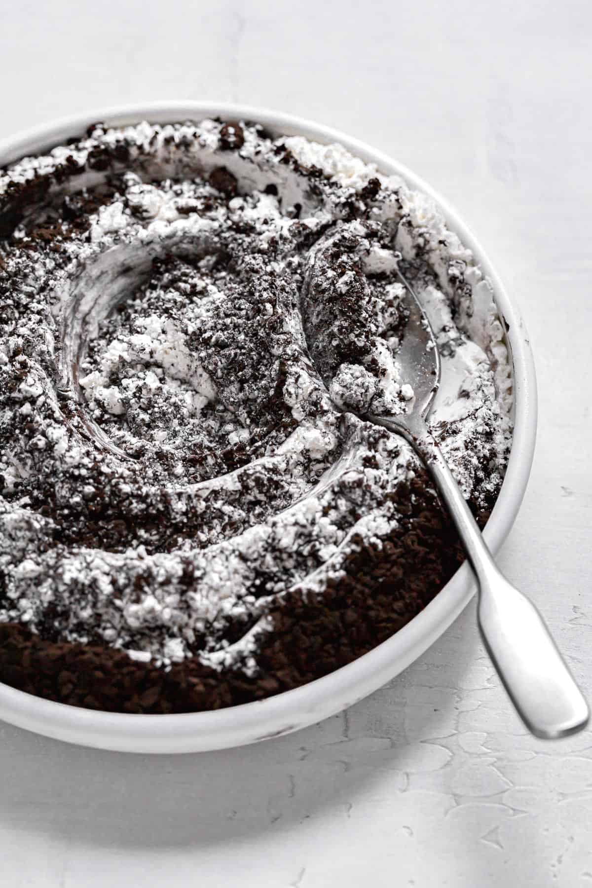 black cocoa powder mixed in flour in white bowl.