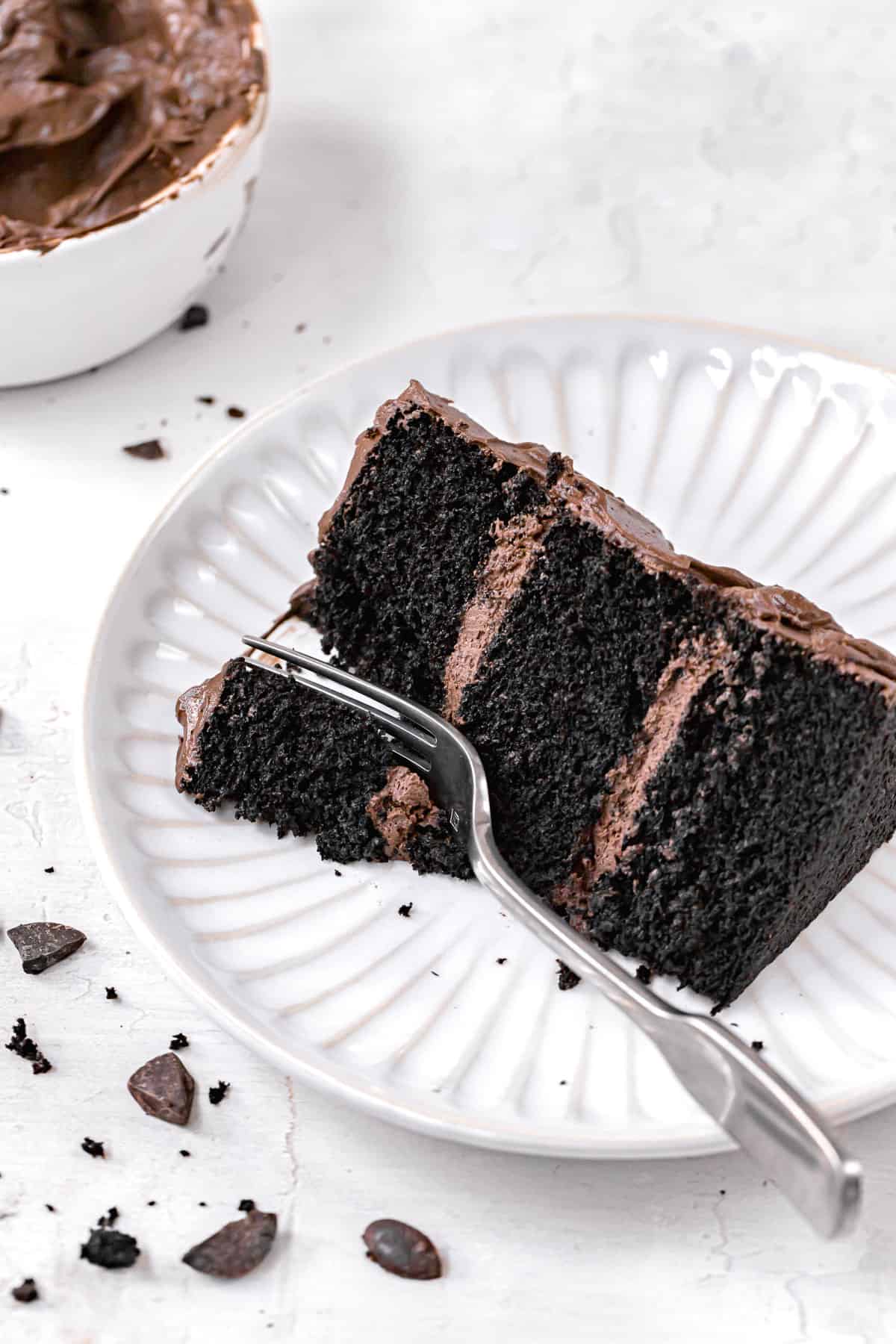 slice of black velvet cake on white plate with fork.