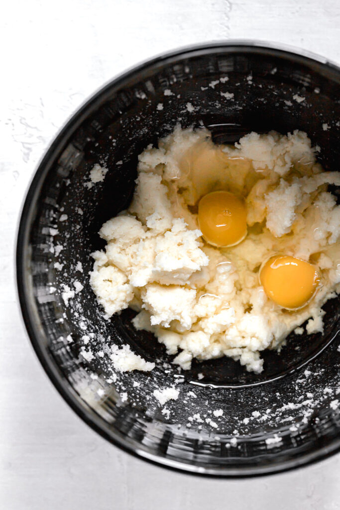 egg yolks and oil added to butter, sugar mixture in black mixing bowl