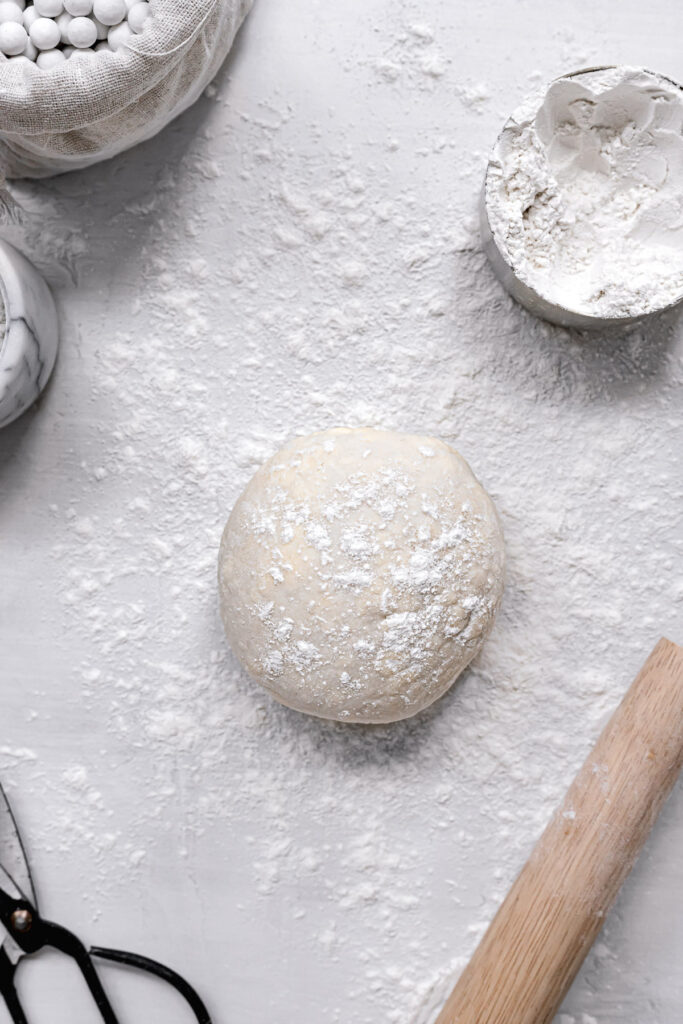 3 ingredient pie dough shaped into ball on floured surface