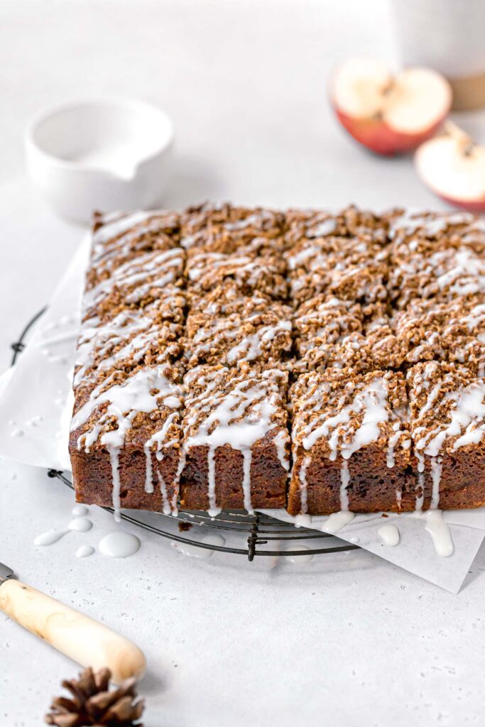 apple streusel cake cut into squares with glaze drizzled on top