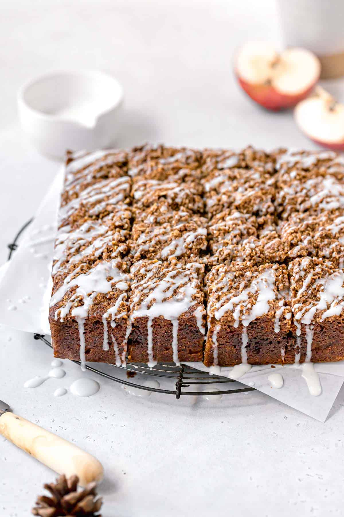 apple streusel cake cut into squares with glaze drizzled on top.