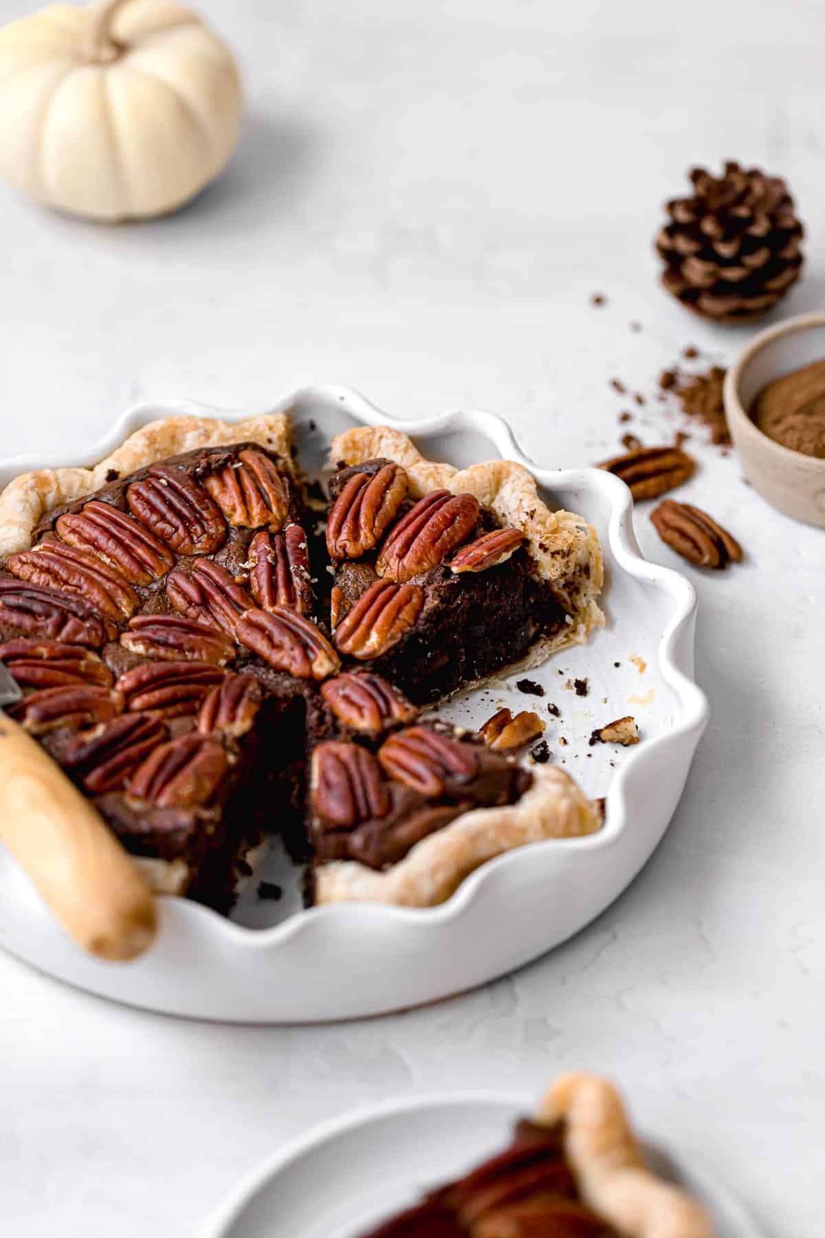 pecan brownie pie with slices cut in white pie dish.