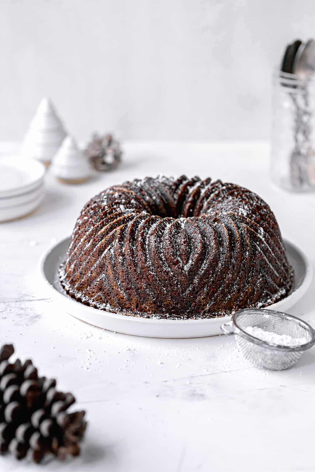 gingerbread bundt cake with powdered sugar on white plate.
