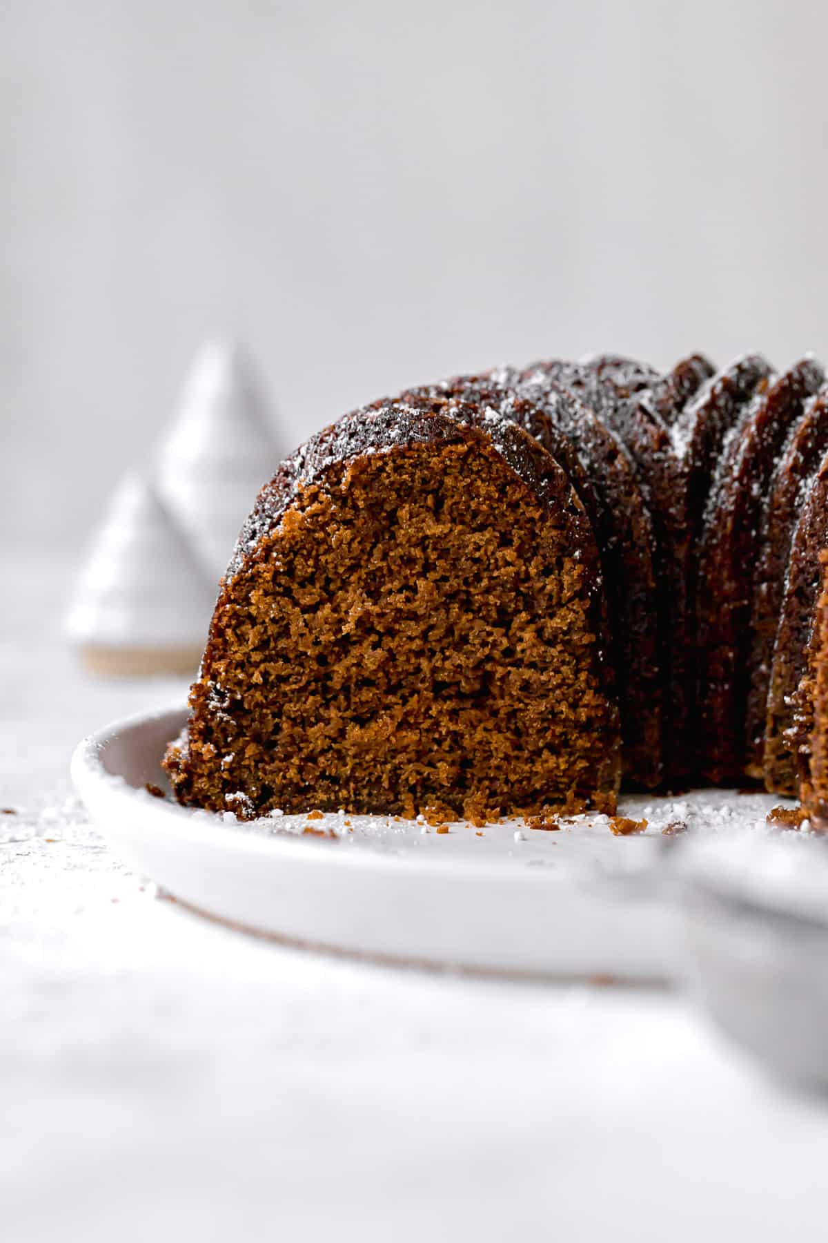 gingerbread bundt cake with powdered sugar cut to show inside texture.