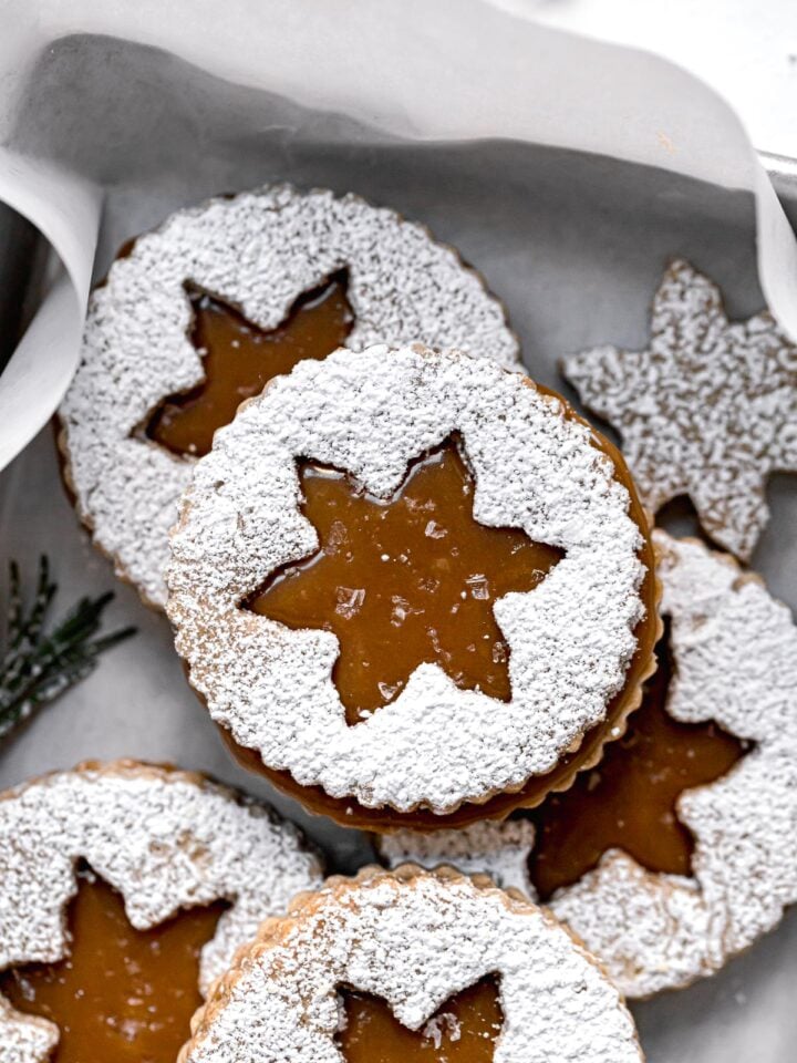 salted caramel christmas linzer cookies piled in small baking sheet