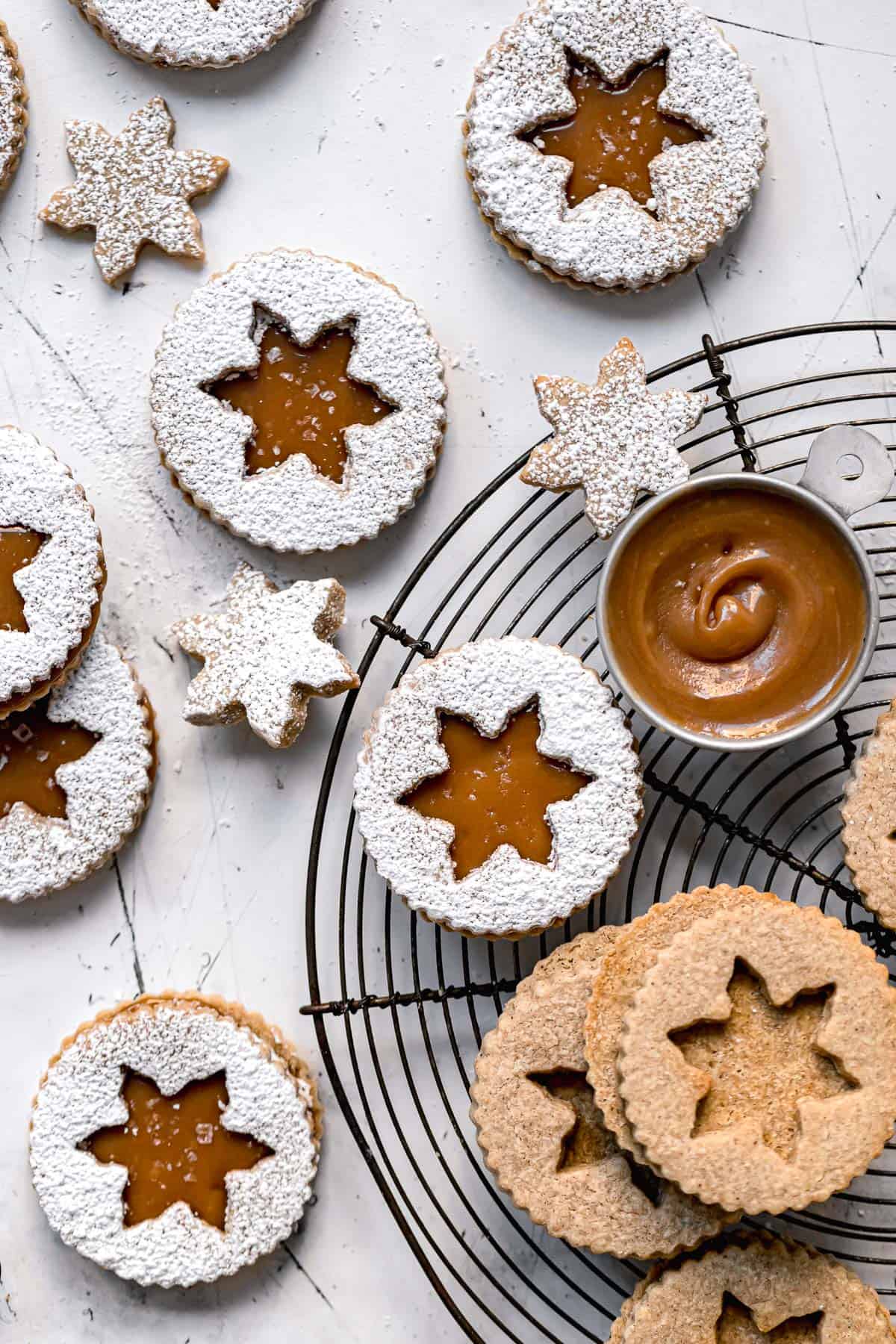 almond flour linzer cookies with caramel sauce and dusted with powdered sugar.