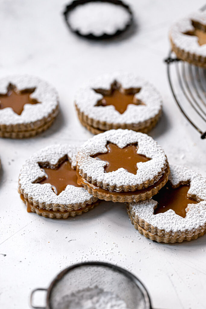 christmas linzer cookie stacked with caramel oozing out the sides