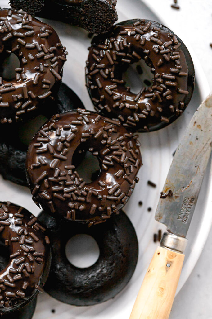chocolate covered donuts on white plate with small knife
