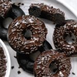 double chocolate glazed donuts with sprinkles layered on white plate