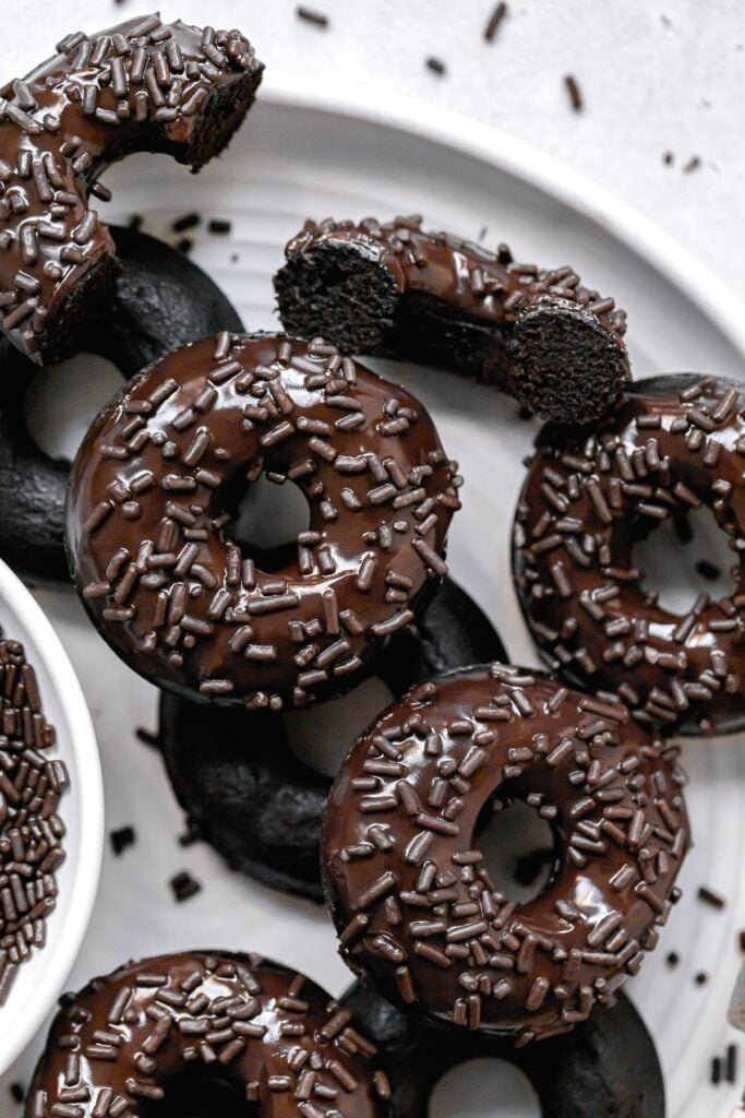 double chocolate glazed donuts with sprinkles layered on white plate