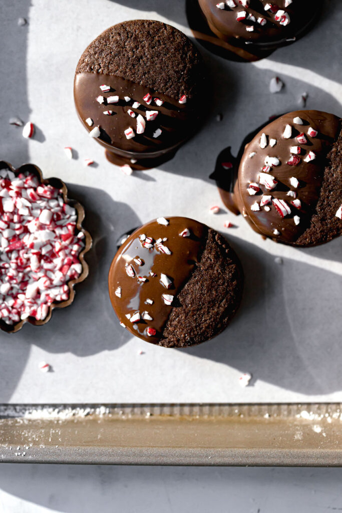 chocolate sable sandwich cookies dipped in melted chocolate and sprinkled with crushed candy canes