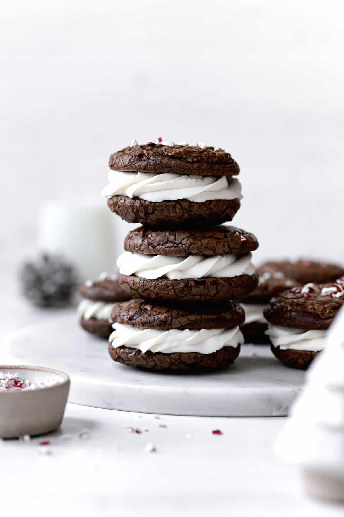 peppermint mocha cookies sandwiched with whipped white chocolate ganache stacked on marble plate.