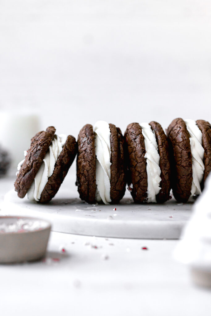 brownie crinkle cookies with whipped white chocolate ganache lined up on a marble plate