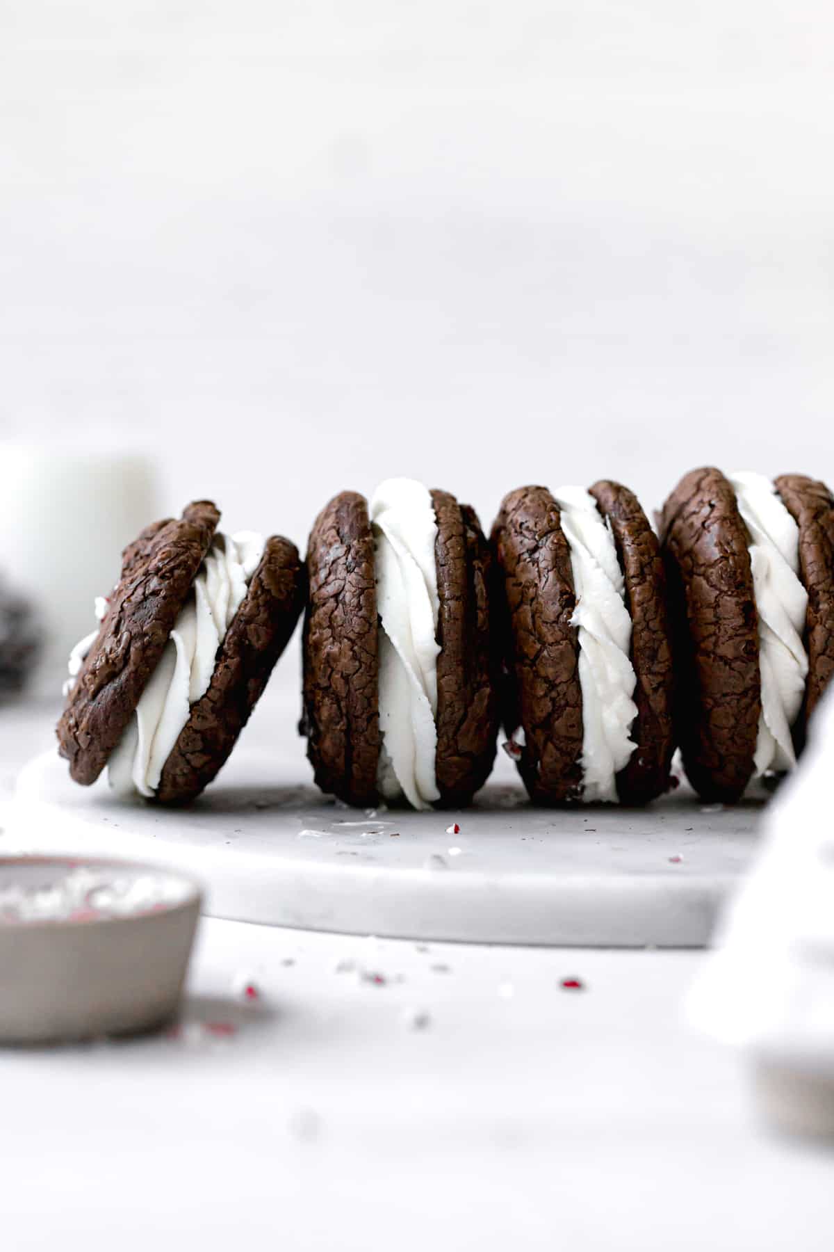 brownie crinkle cookies with whipped white chocolate ganache lined up on a marble plate.