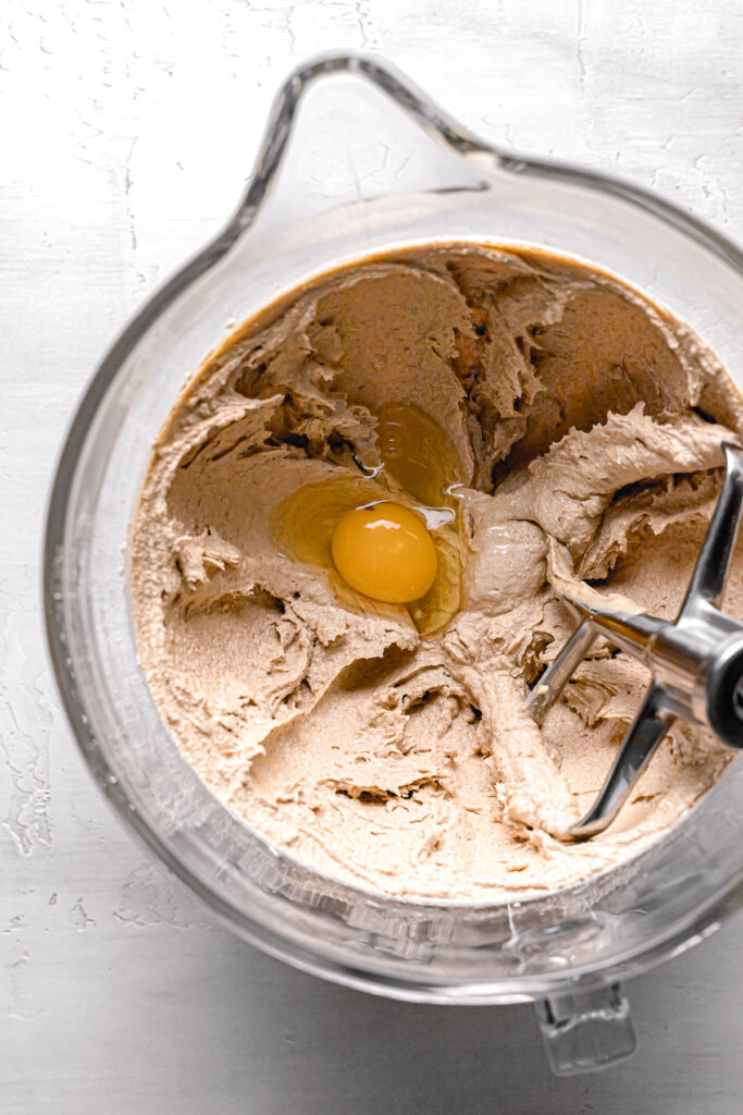 egg added to butter, peanut butter, sugar mixture in glass bowl