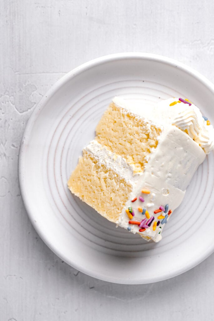 one slice of vanilla birthday cake on white plate