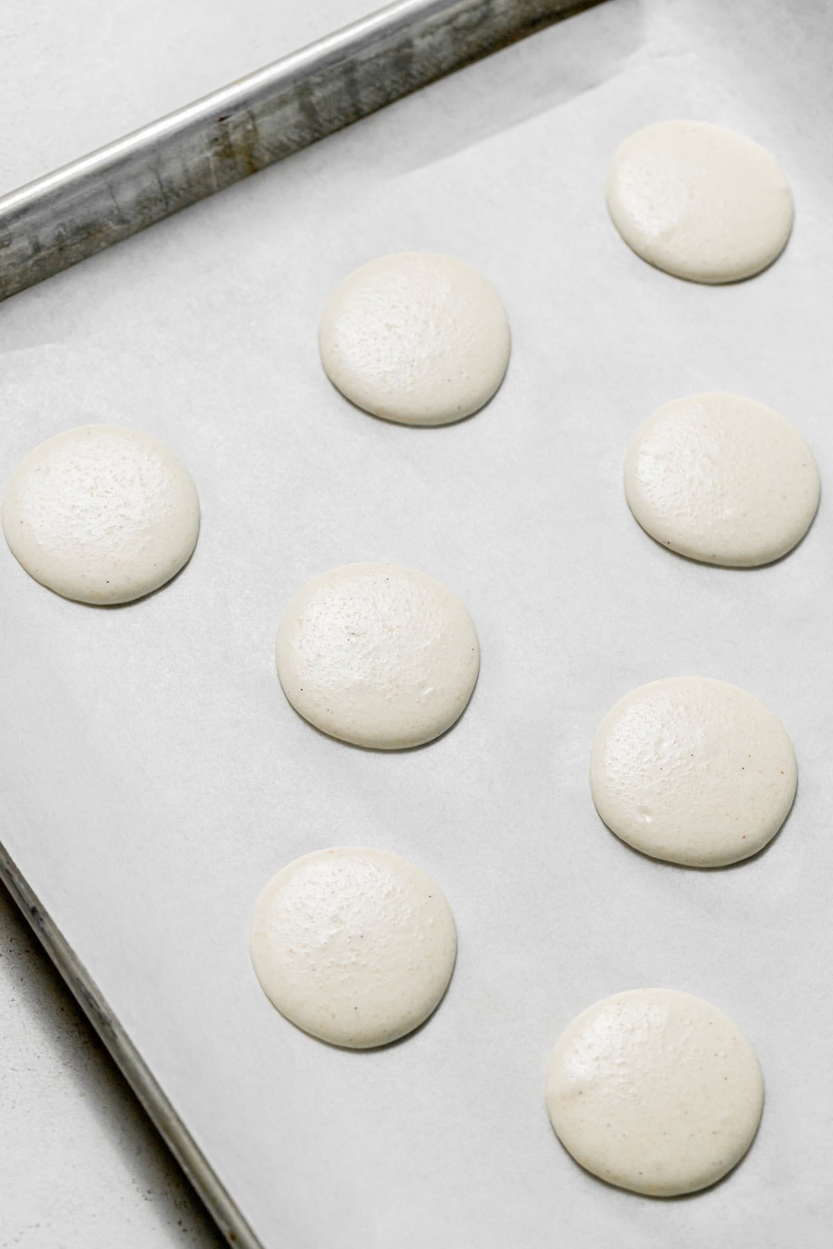 macaron batter piped onto baking sheet.