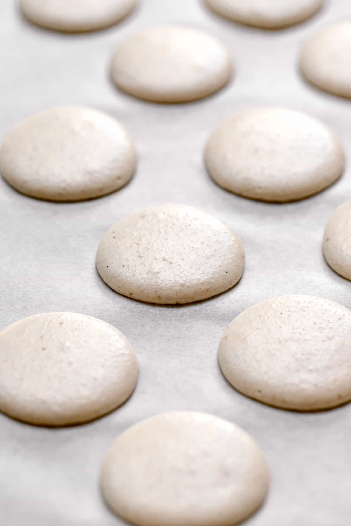 piped macaron batter on parchment lined baking sheet.