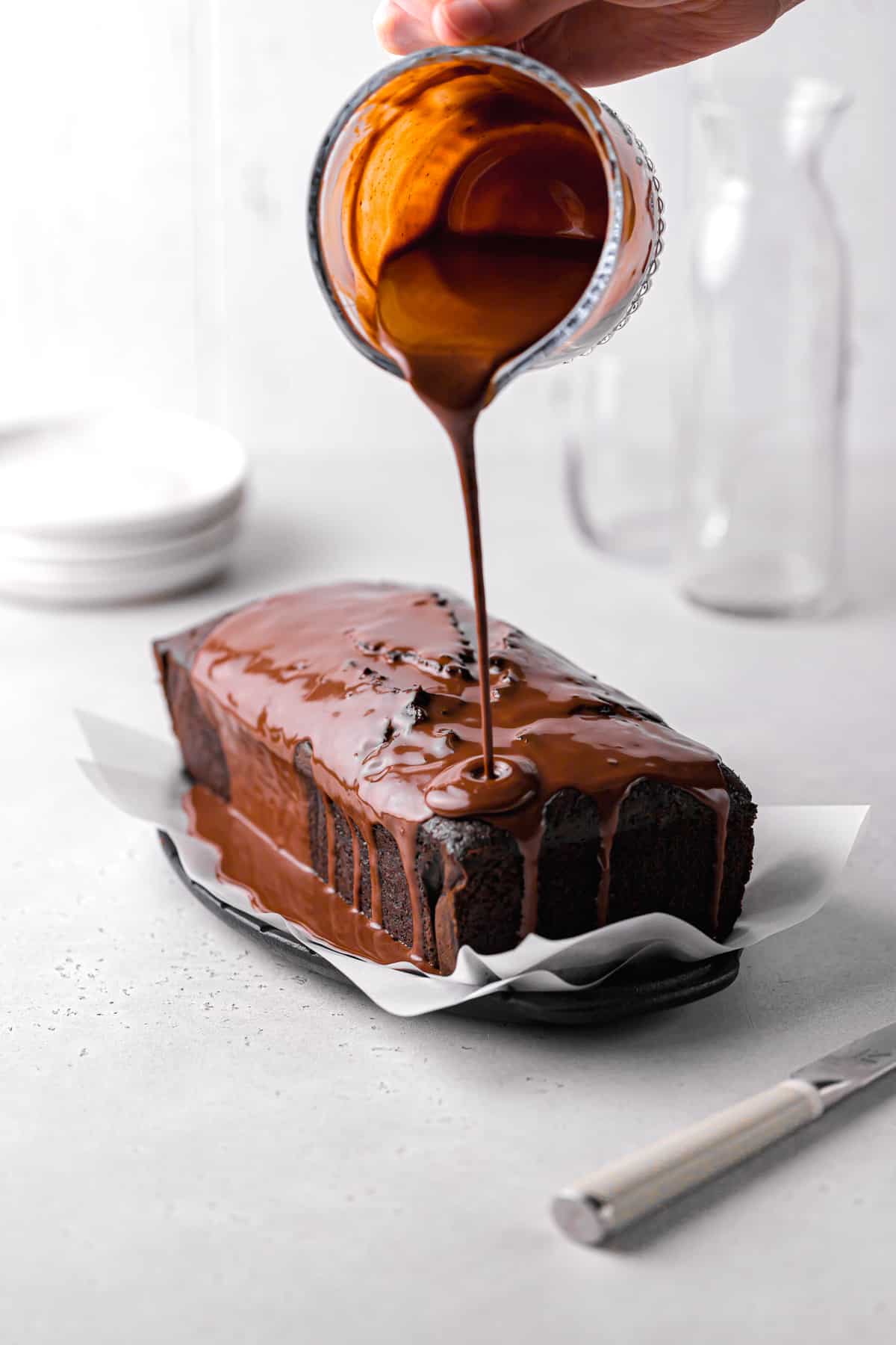 chocolate glaze being poured over chocolate pound cake.