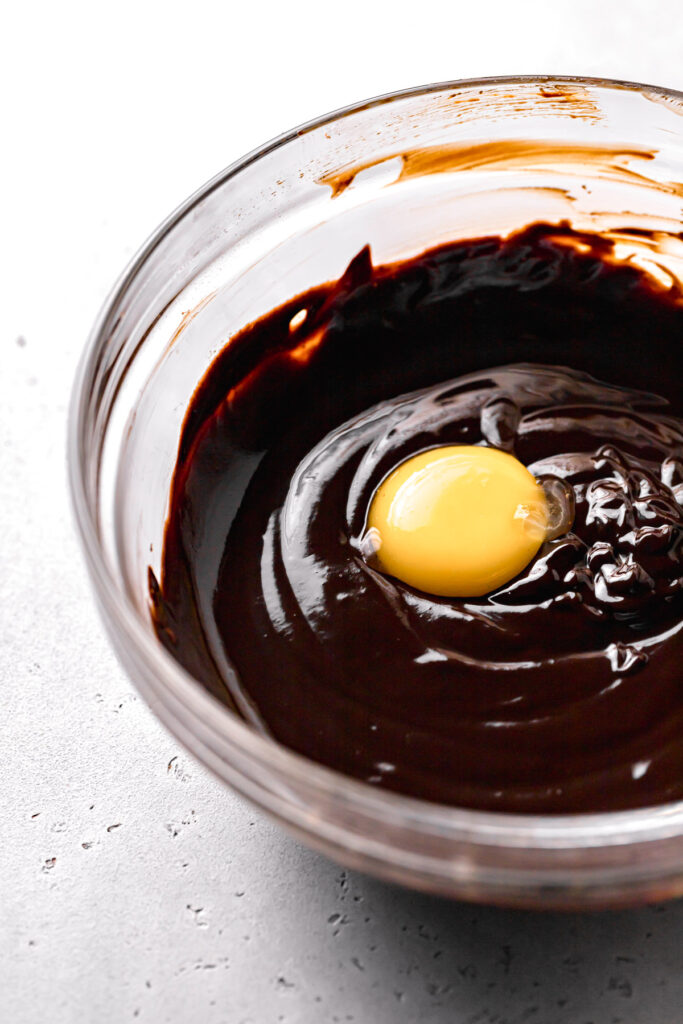 egg yolk added to chocolate mixture in glass bowl