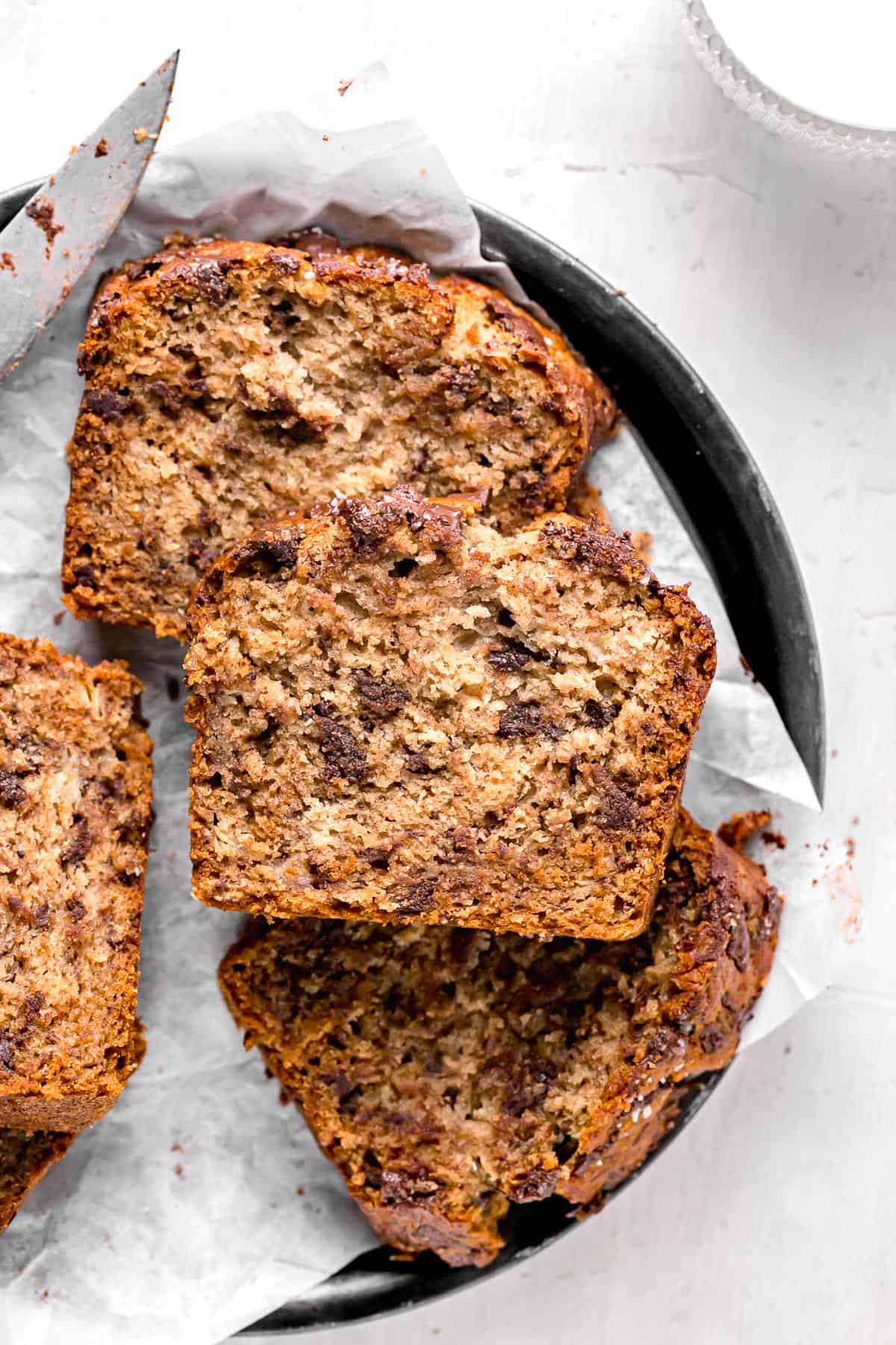 slices of banana bread made with olive oil and honey piled on plate.