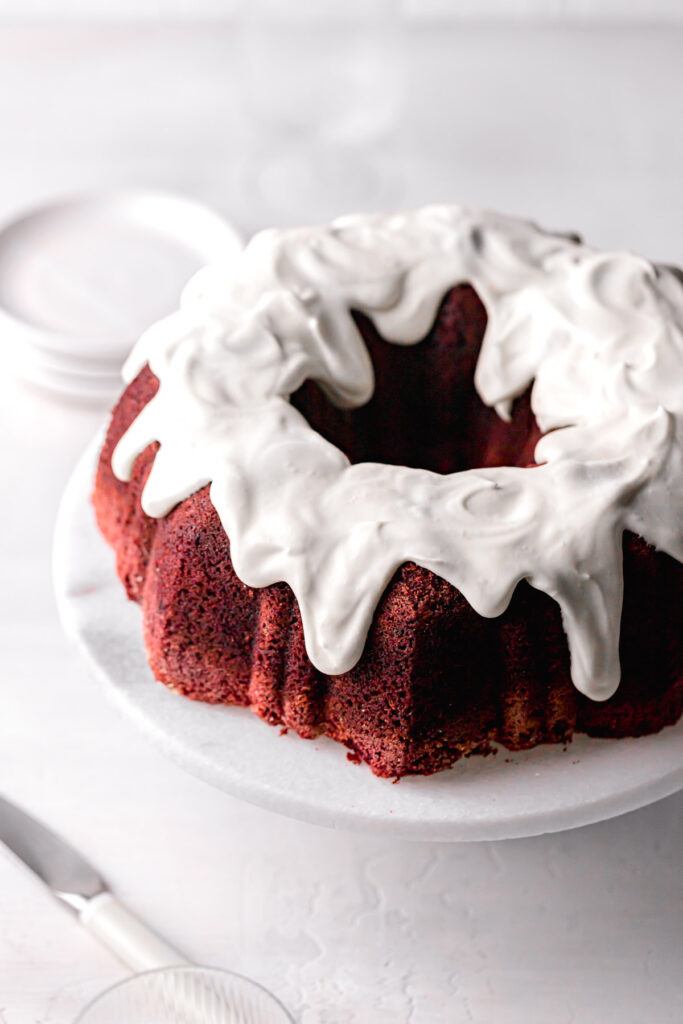 red velvet bundt cake with cream cheese frosting on marble cake stand