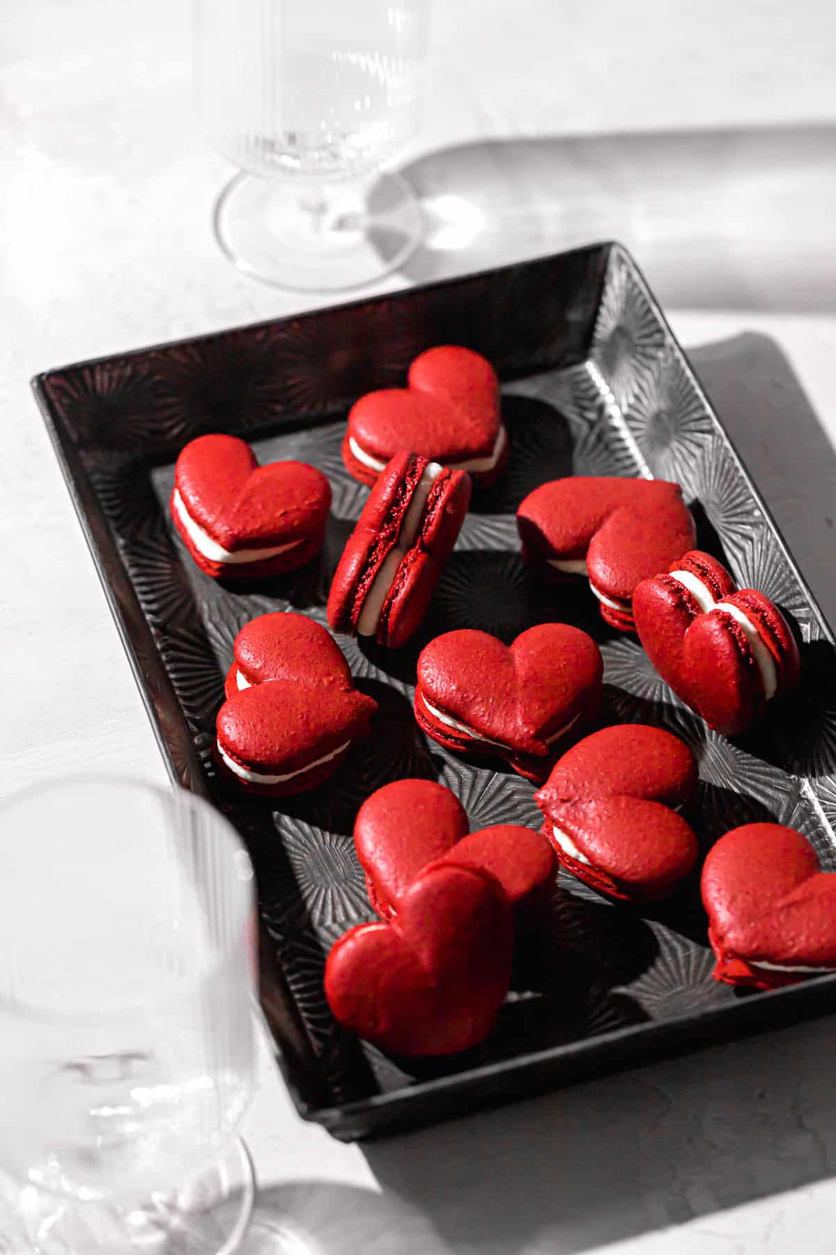 red velvet macarons shaped as hearts and filled with mascarpone frosting.