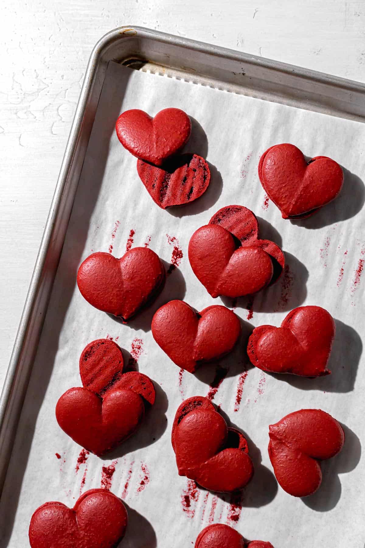 red velvet macarons baked on a tray with parchment paper.