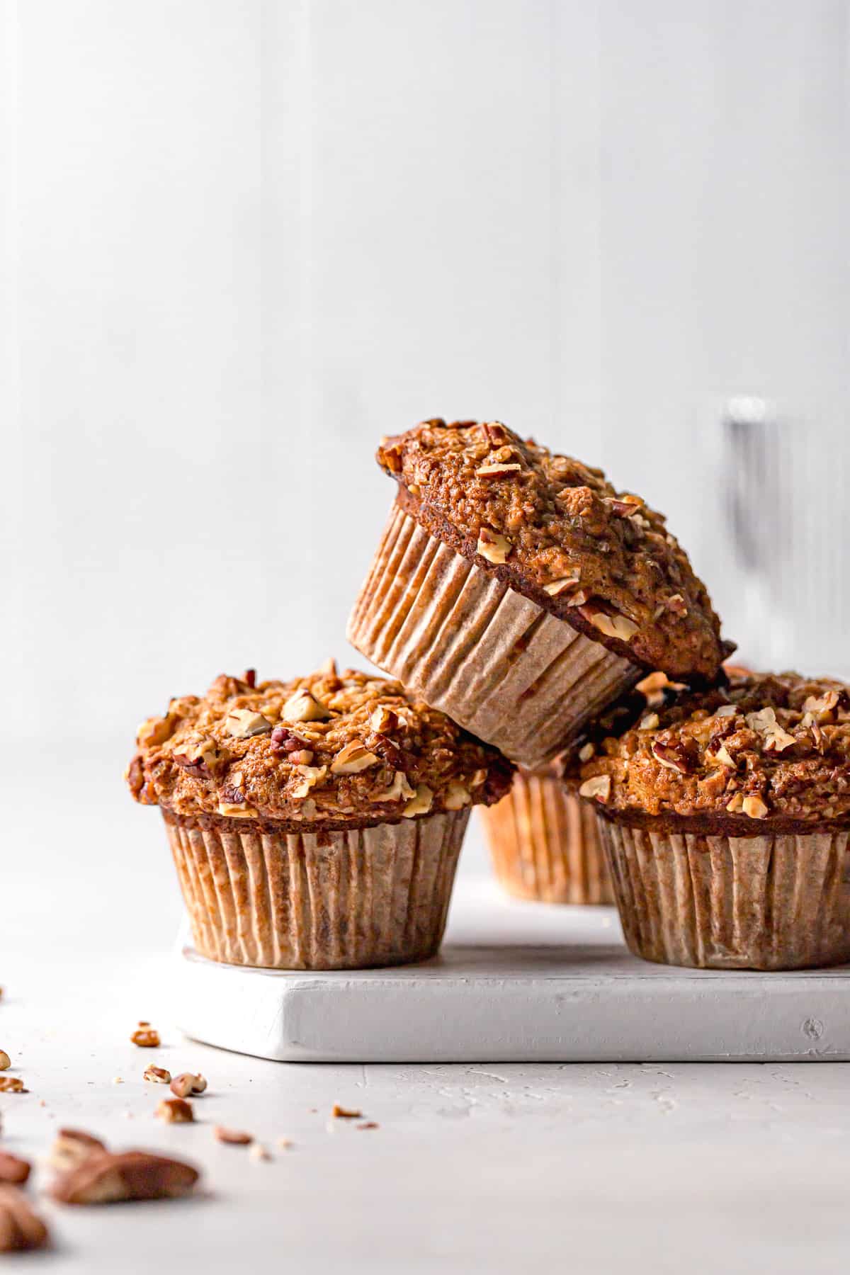 banana carrot muffins stacked on white wooden board.