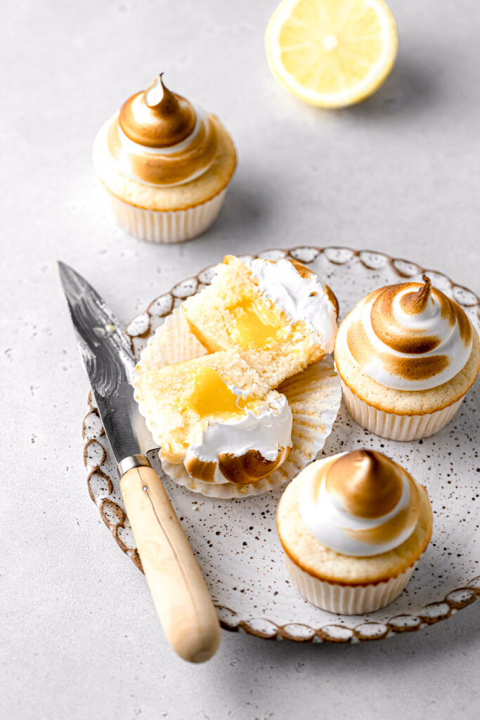 lemon meringue cupcakes on plate with one cut in half
