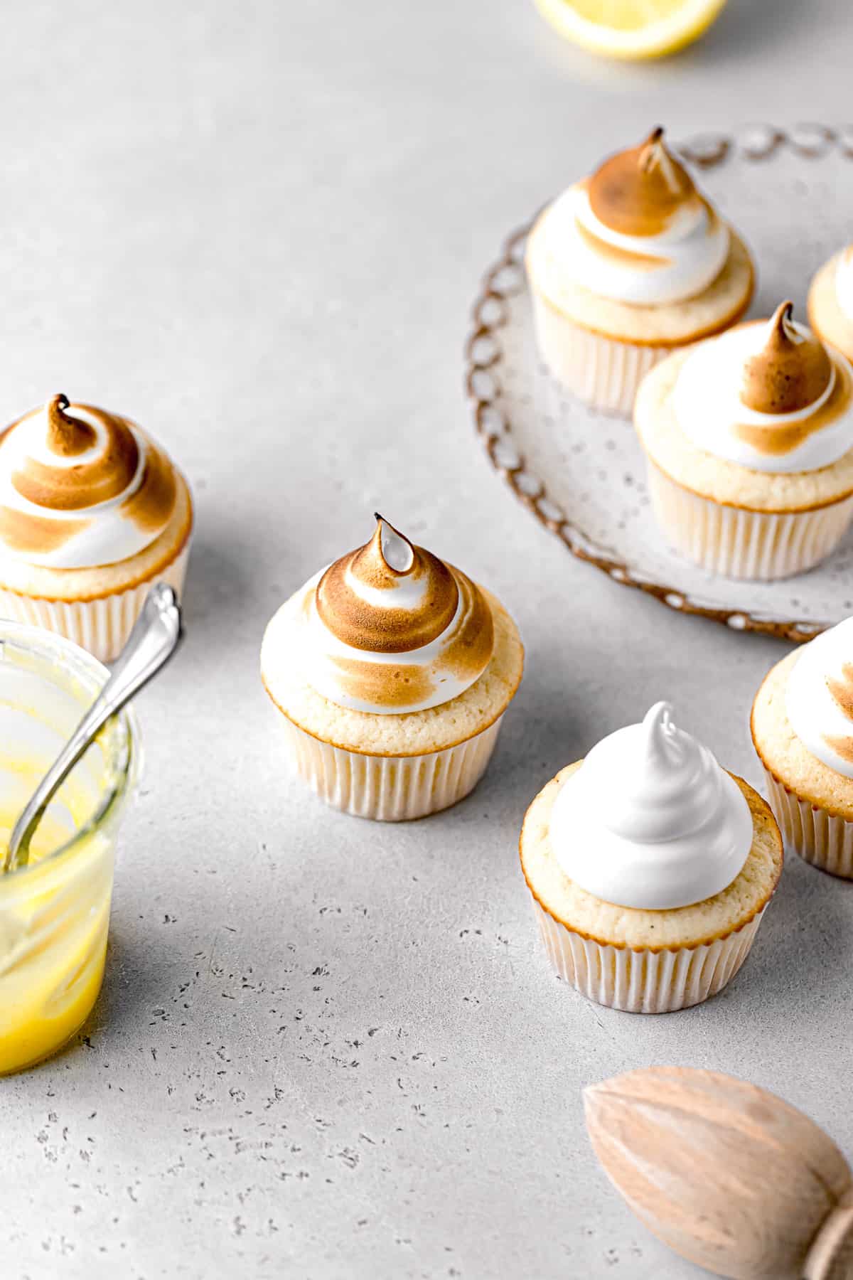 lemon meringue cupcakes on plate and surrounding it.