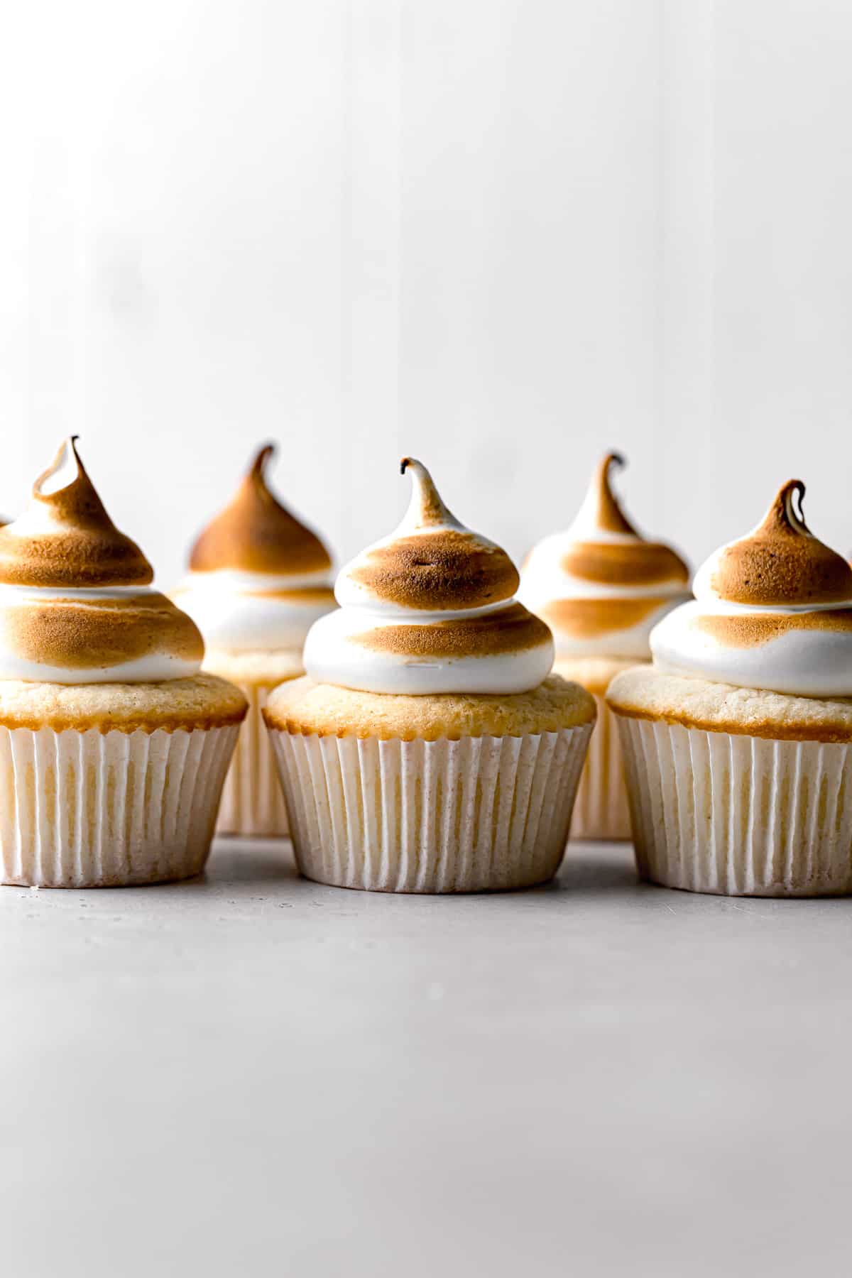 lemon cupcakes with torched meringue lined up in a row.