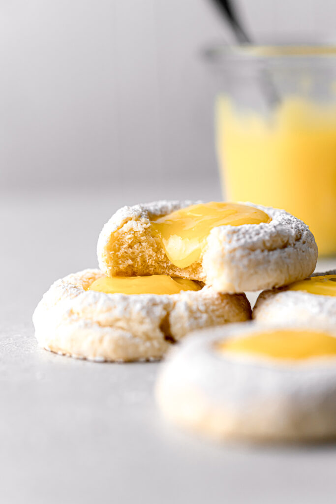 lemon curd thumbprint cookies stacked with bite taken out of top cookie