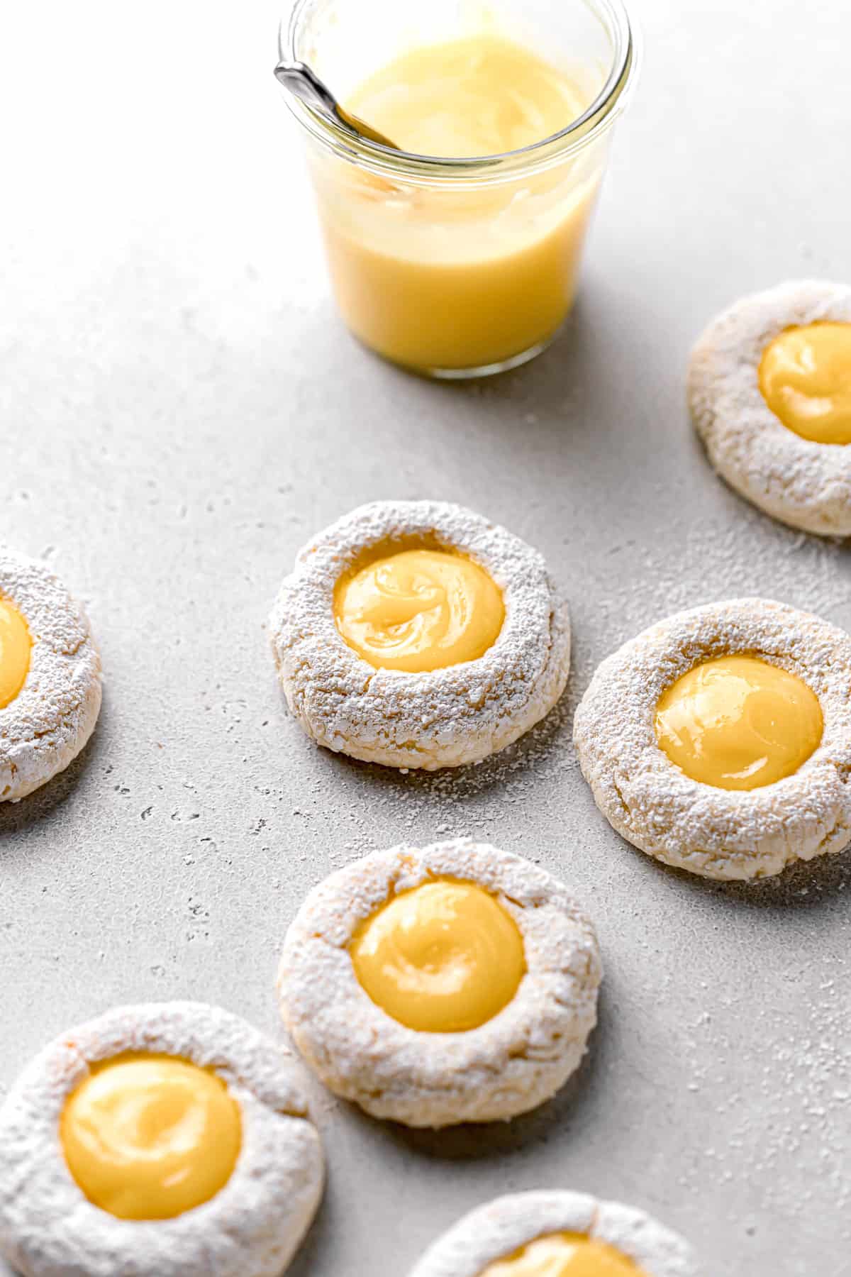 lemon curd cookies with powder sugar and a glass of tart lemon curd.