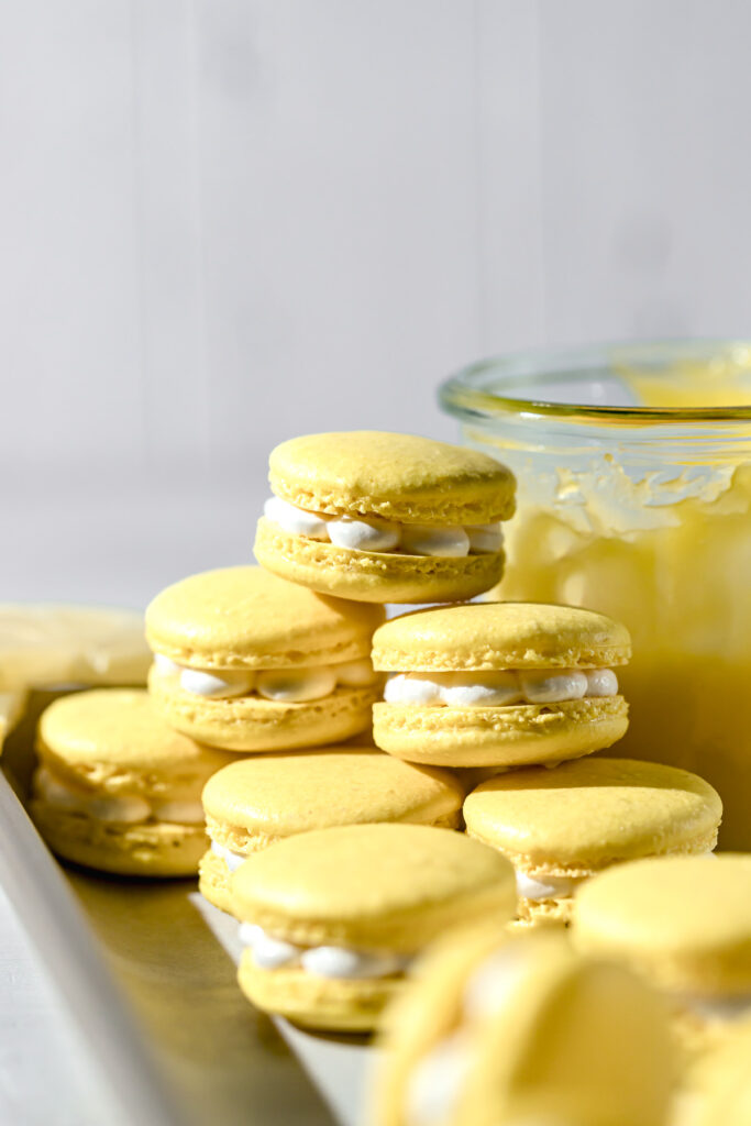 lemon macarons stacked up against jar of lemon curd