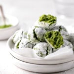 matcha amaretti cookies piled on stacked white plates