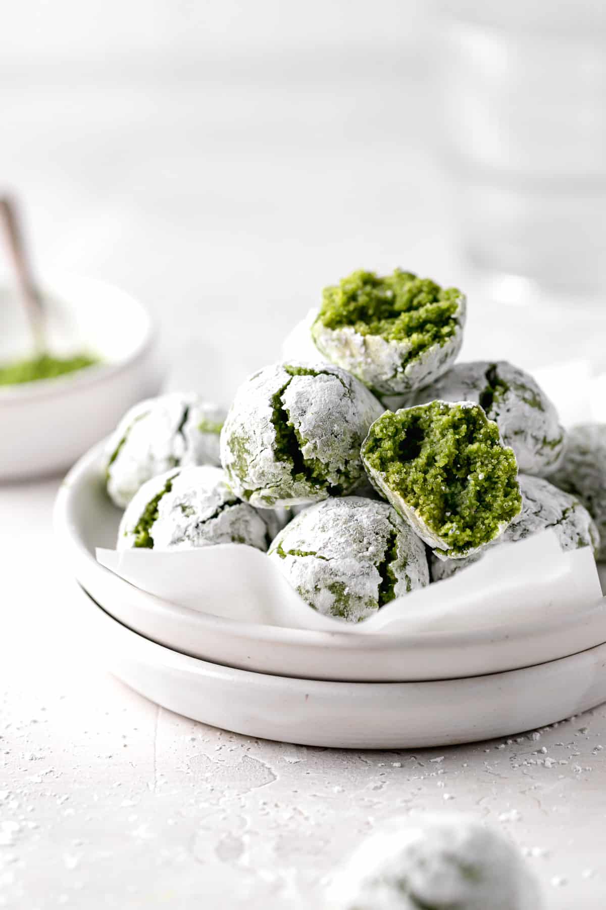 matcha amaretti cookies piled on stacked white plates.