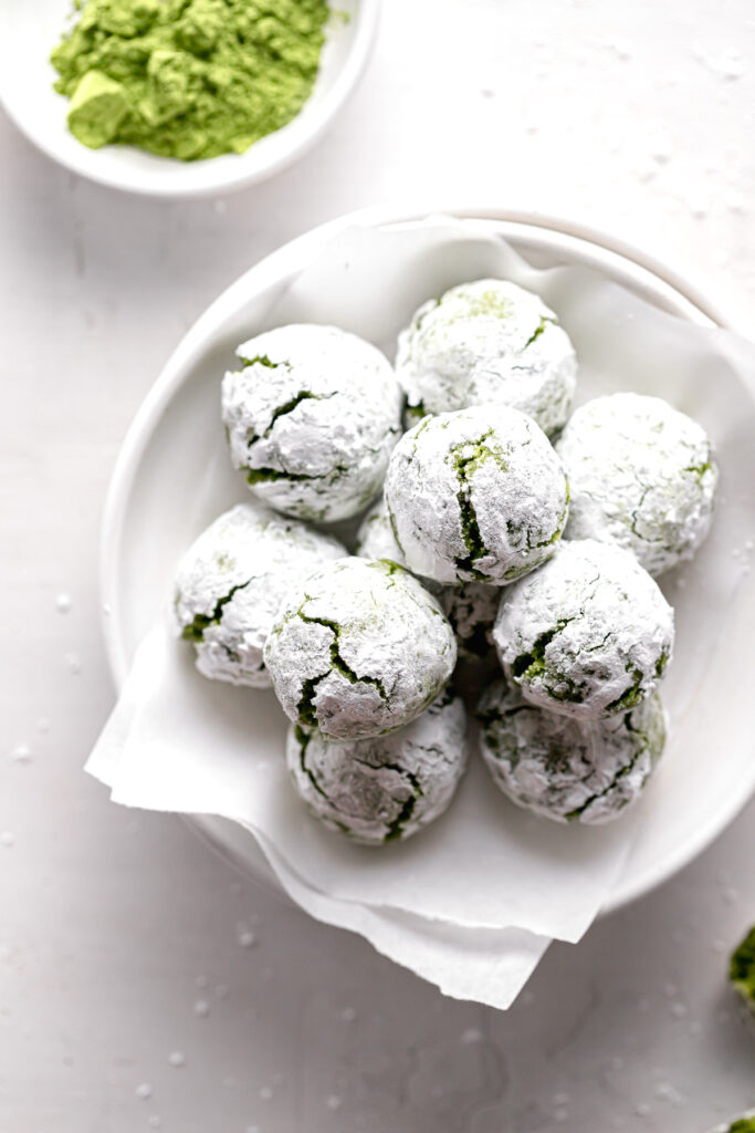 matcha crinkle cookies piled on parchment lined plate