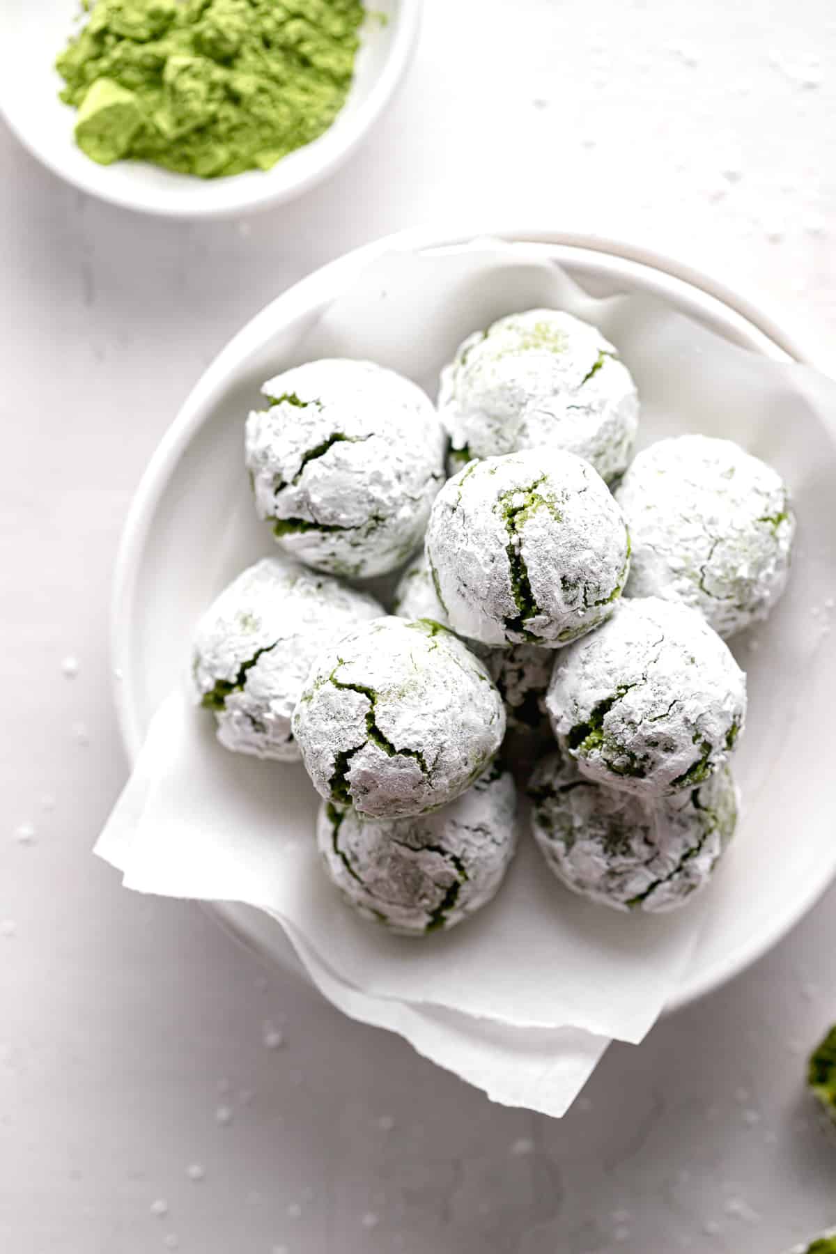matcha crinkle cookies piled on parchment lined plate.