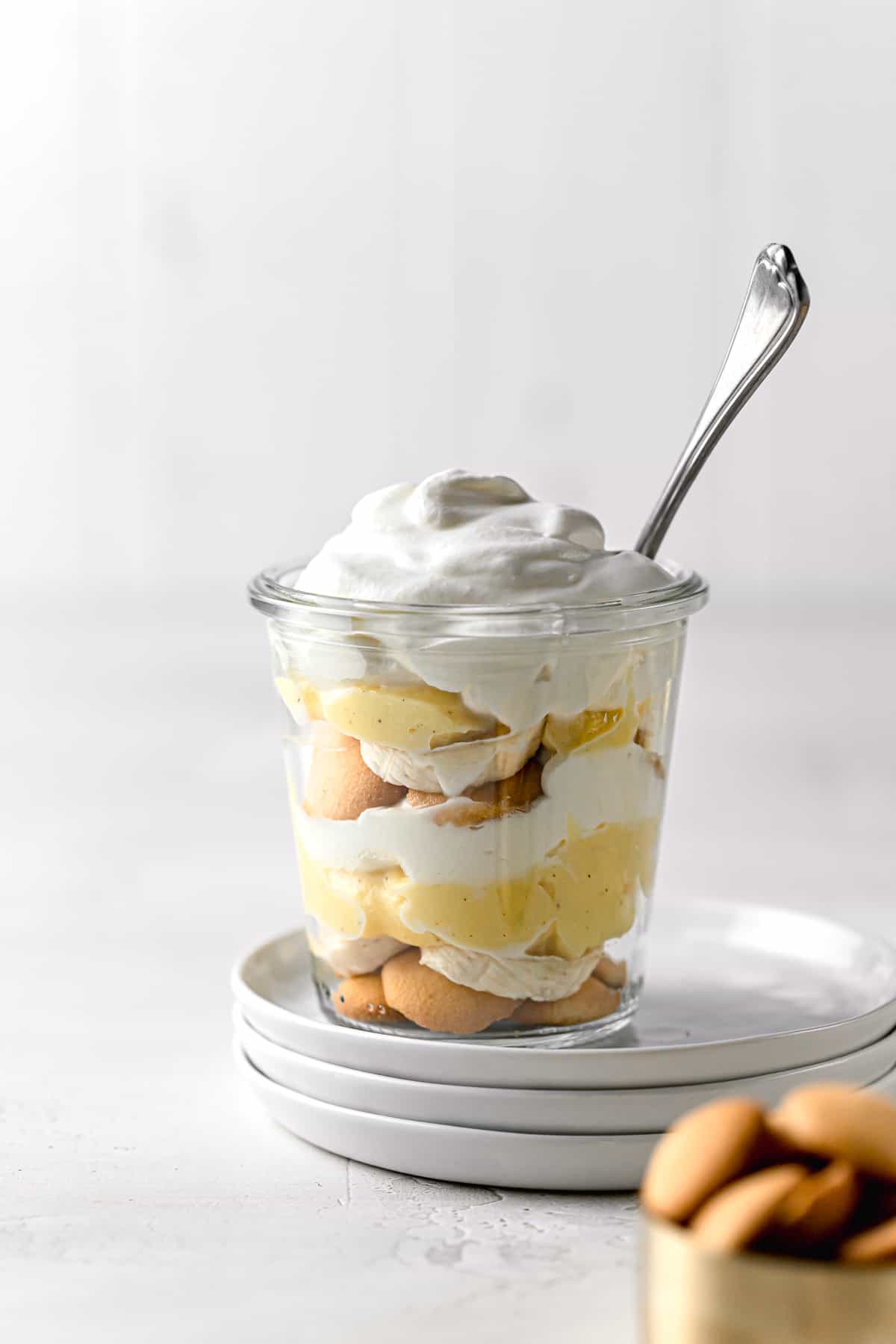 banana pudding jar with spoon on top of stacked plates.